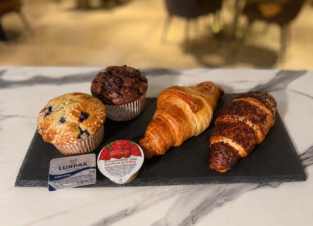 Selection of muffins and croissants on a slate board